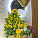 Canasta con girasoles, rosas, frutas, y globo con helio