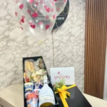 Caja con dulces, fresas con chocolate, botella de JP Chenet y globos con helio