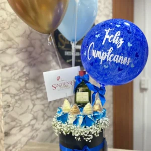 Cilindro con rosas azules, fresas con chocolate, botella de Buchanas y globos con helio